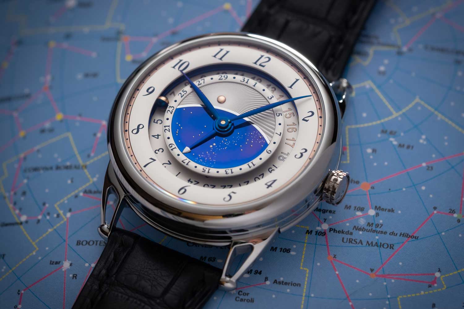 The centre of the dial represents both day and night, with a pink gold sun in the upper half and the night sky in the lower half, set in blued titanium.