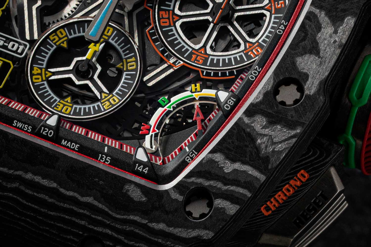 The dial of the RM 65-01 features the hour and minute hand, hour indexes and small seconds are all rendered yellow; the chronograph 12-hour counter at nine o’clock and the 30-minute counter at three o’clock are both in orange, as is the chronograph seconds hand; superimposed on top of the chrono seconds hand is the blue split seconds hand; bottom right, you’ll find the gear selector and top left you’ll find the date (©Revolution)