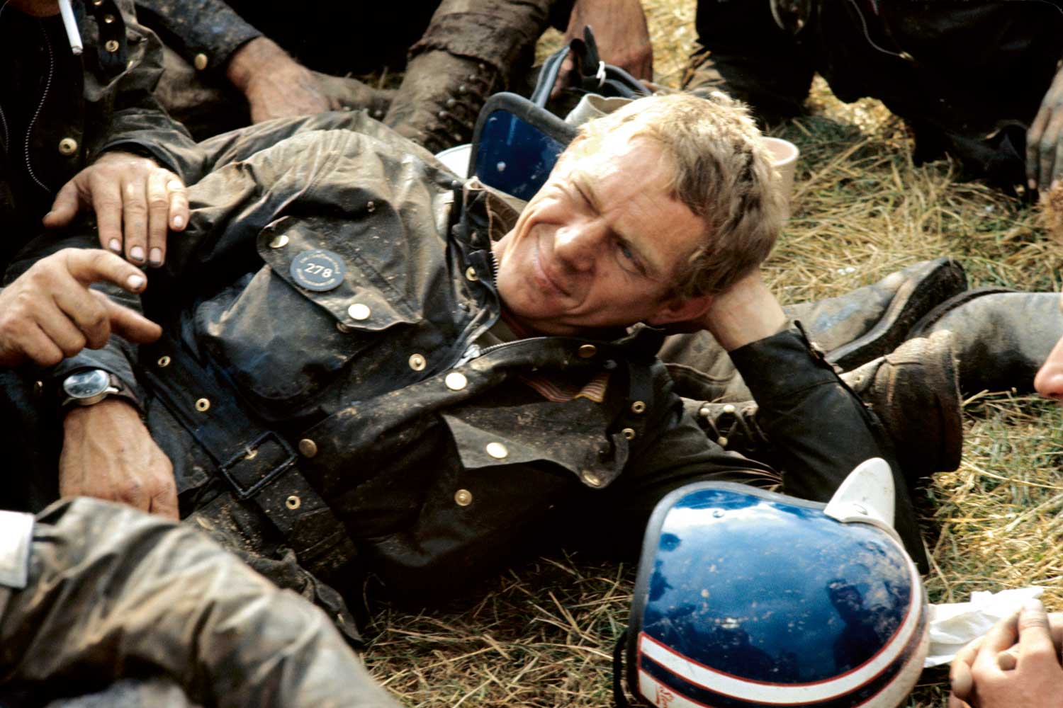 Steve McQueen resting after his run-out on the 1964 ISDT track. Each evening after the race (300km on average on terrible paths), the runners used to collapse on the grass, covered in mud and oil. Visible on his wrist is the Hanhart 417 ES (Photo by François Gragnon / Paris Match via Getty Images)