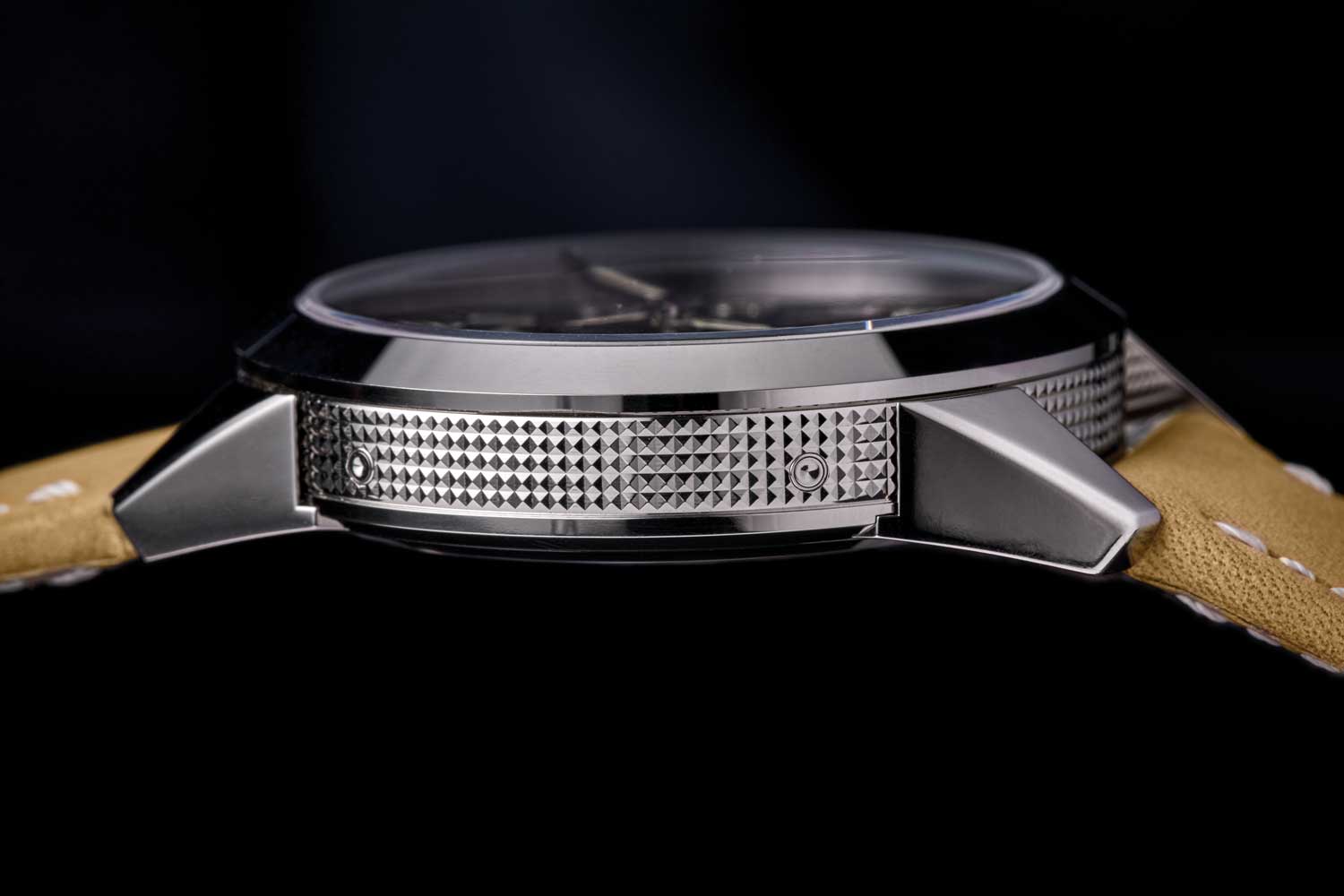The hobnail pattern on the bezel flows seamlessly beneath the lugs, which are attached to the caseback