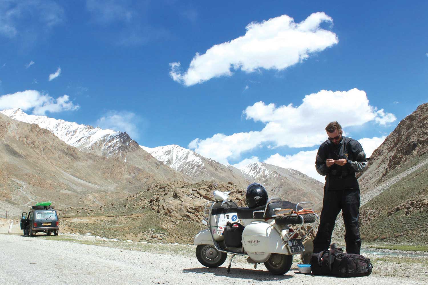 Laurens de Rijke doing maintenance on his Vespa bike along the Pamir Highway, Tajikistan.