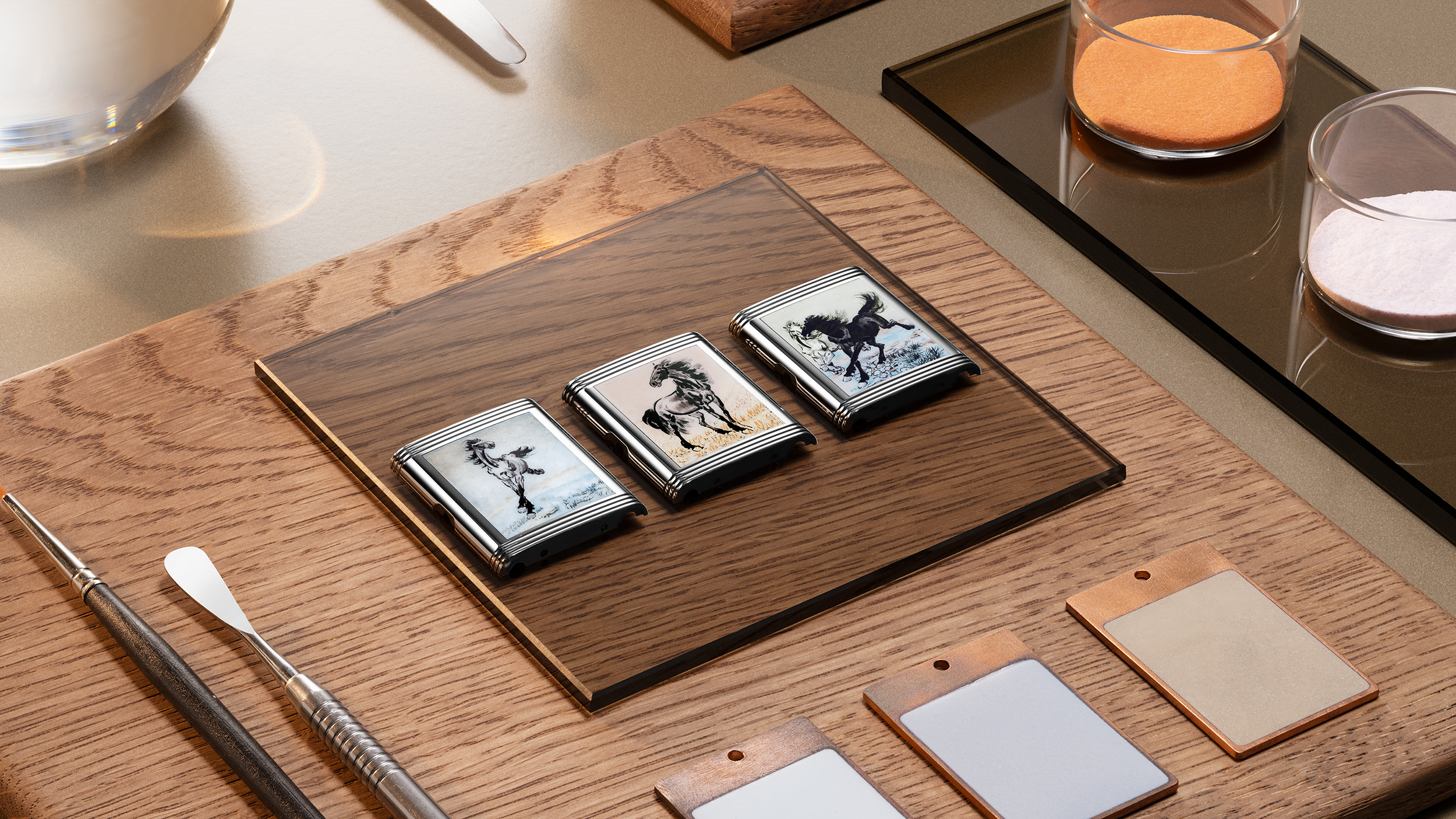 Three Reverso casebacks laid out on a wooden tray, each depicting a different Xu Beihong horse painting in enamel
