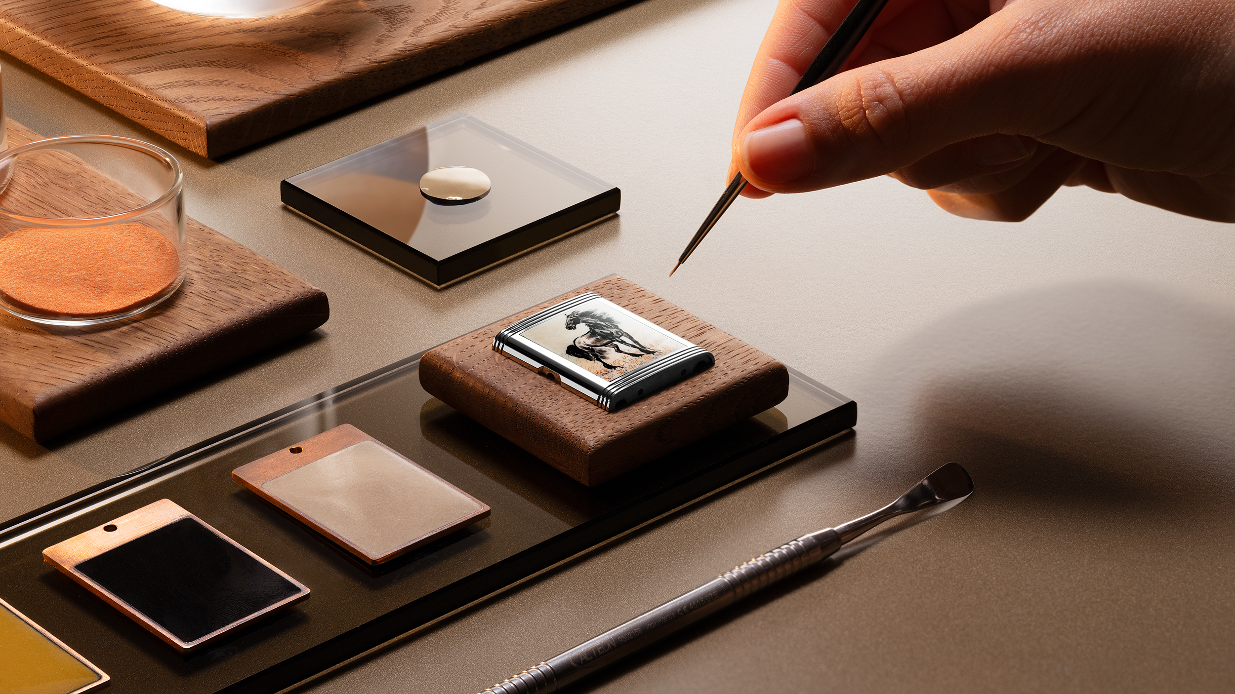 Close-up of a craftsman’s hand painting a miniature horse scene on the Reverso caseback, illustrating the 80 hours of delicate enamel work required to faithfully reproduce Xu Beihong’s original artwork.
