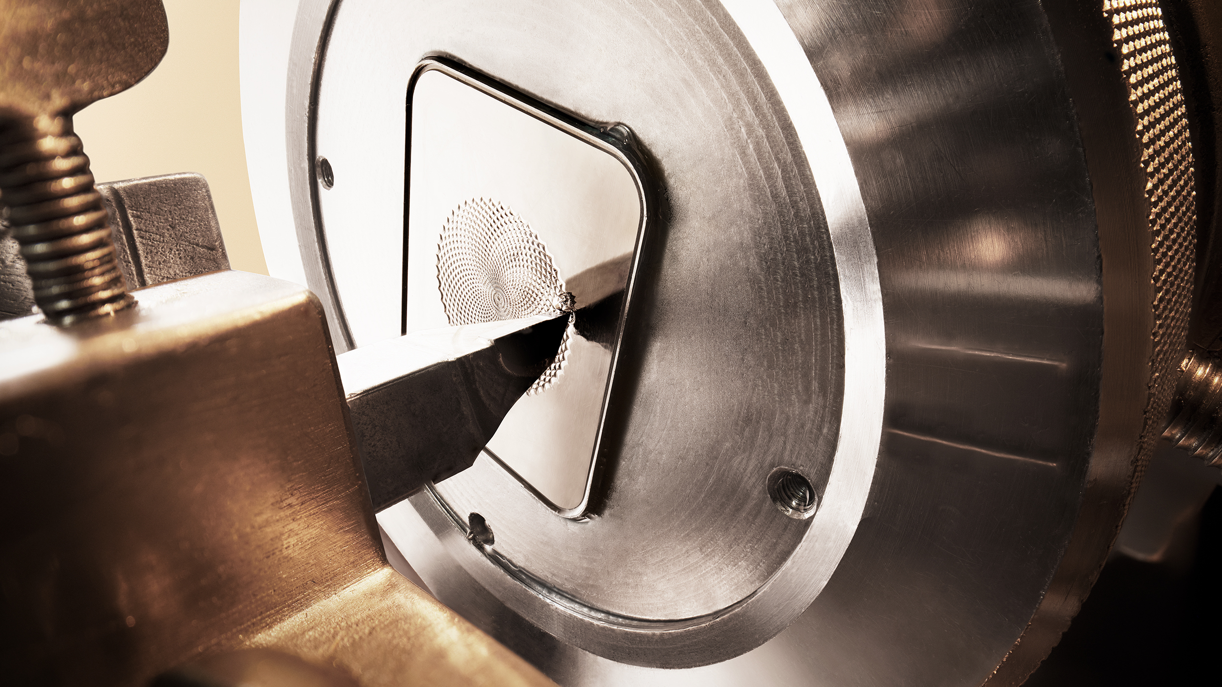 Close-up of a rose engine cutting a precise guilloché pattern into the square Reverso dial surface as part of the guillochage process