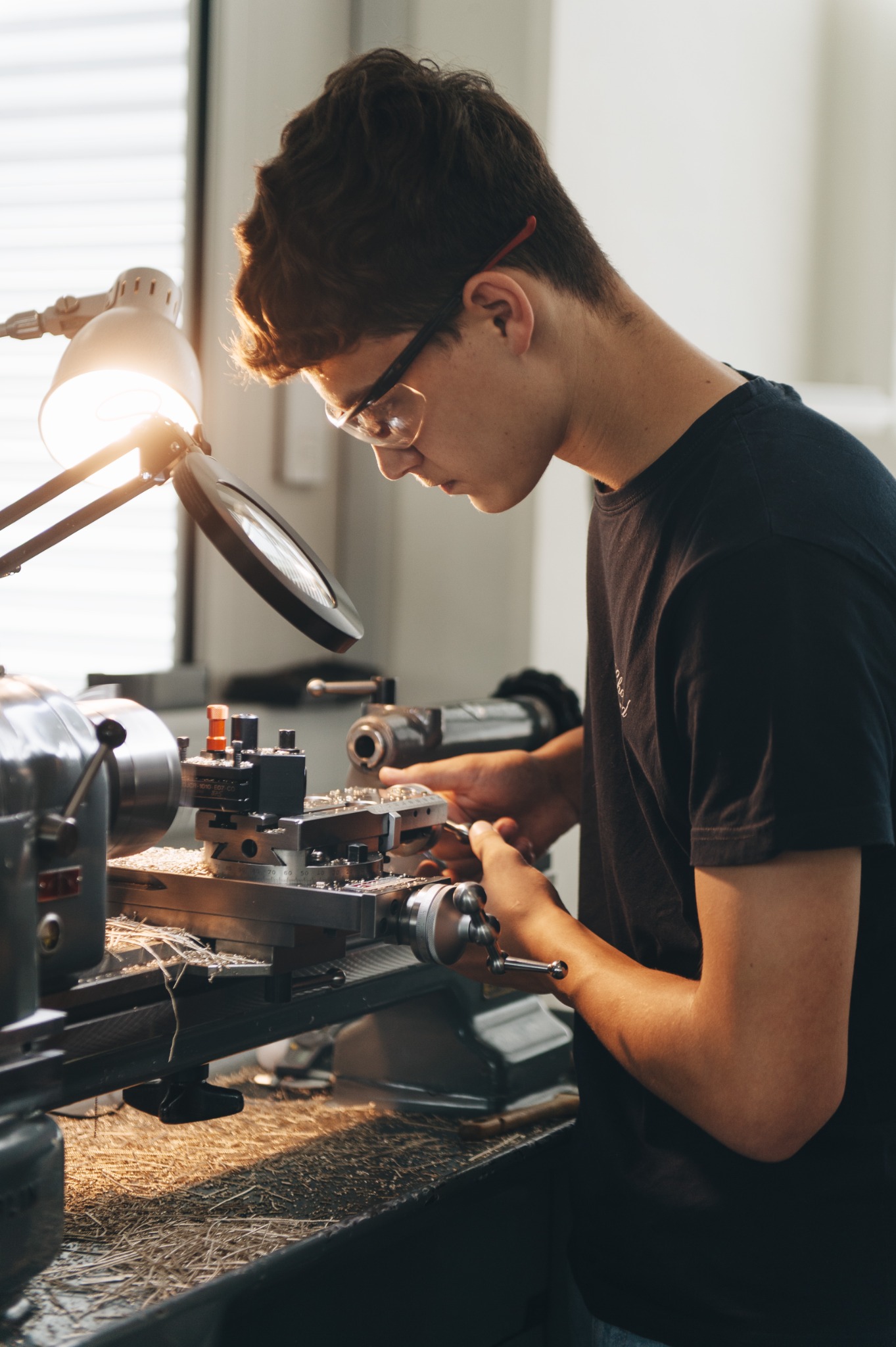 Young artisan operating a traditional lathe to shape components for the Naissance d'une Montre 3