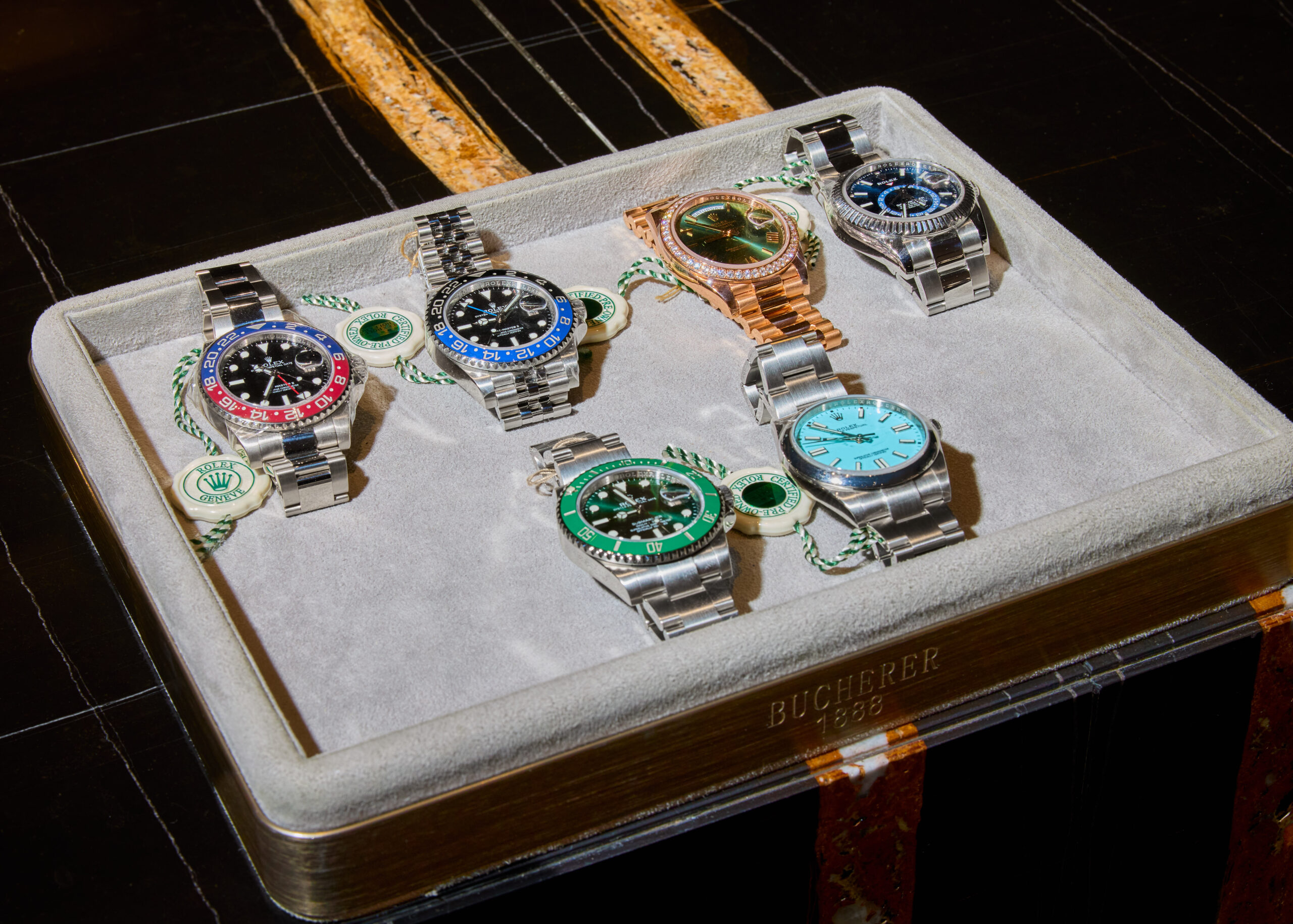 Selection of Rolex watches on a display tray with certification tags in a Bucherer Certified Pre-Owned setting