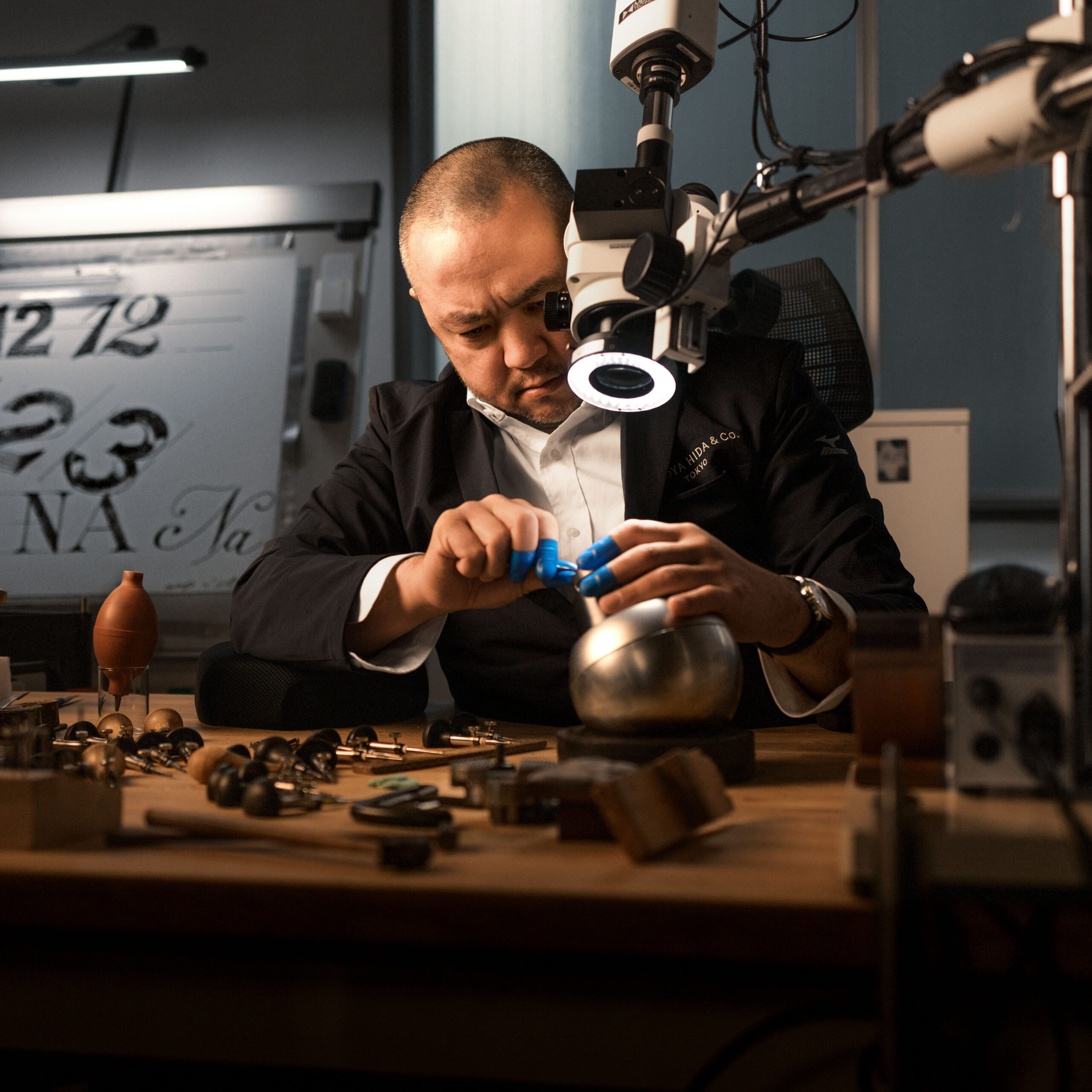 Watchmaker working under a microscope at the Naoya Hida & Co. Tokyo atelier, hand-engraving dial numerals