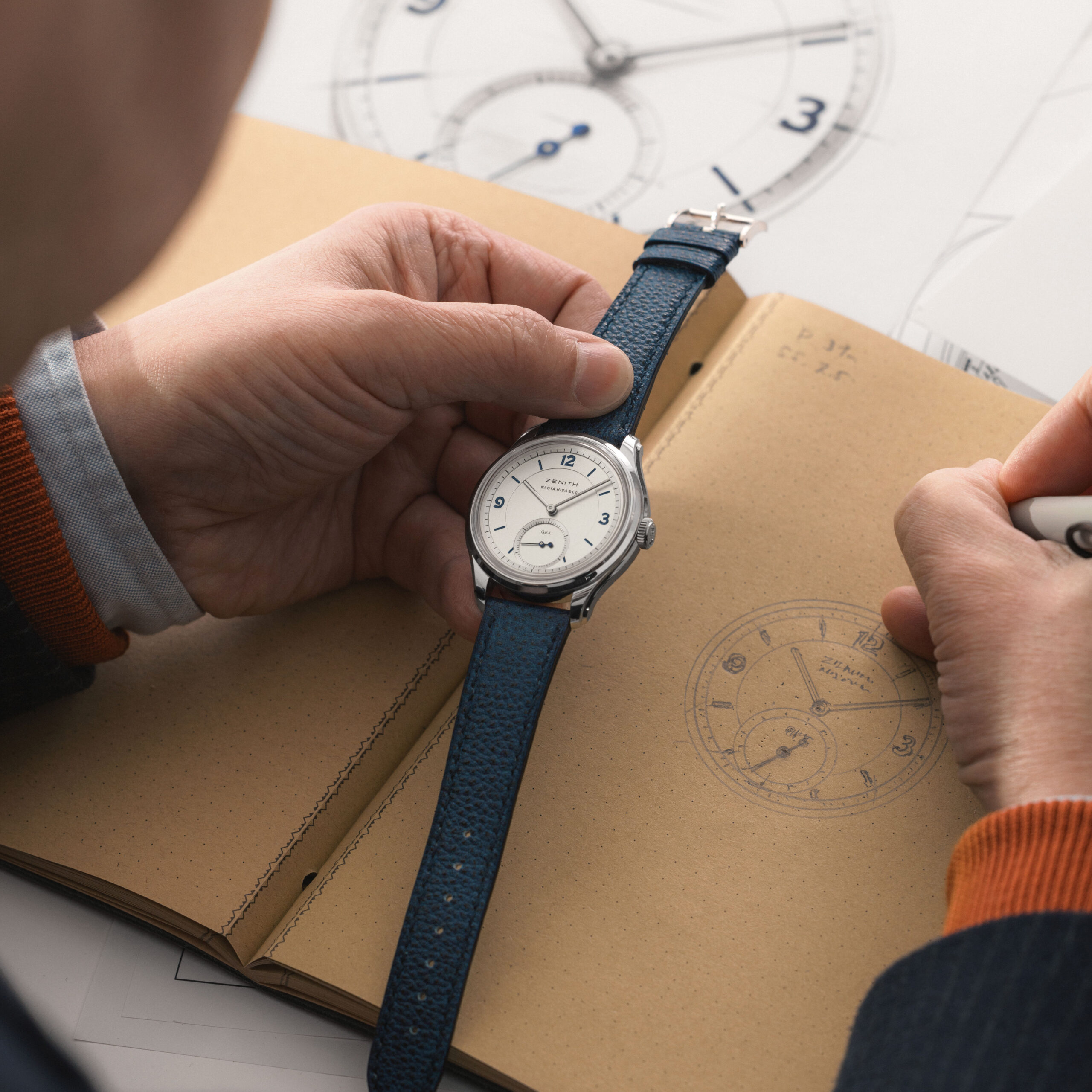 Naoya Hida holding the Zenith G.F.J. Calibre 135 Double Signed watch over hand-drawn dial sketches